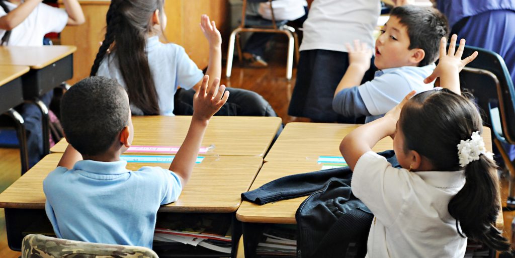 A student raising their hand in a classroom